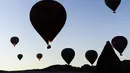 Pemandangan siluet balon udara panas yang terbang di atas Nevsehir di wilayah Cappadocia, Turki (5/9). Wisatawan dapat menjelajah dengan menaiki balon udara, terbang di atas kota batu kuno dan pegunungan-pegunungan yang indah. (AFP Photo/Yasin Akgul)