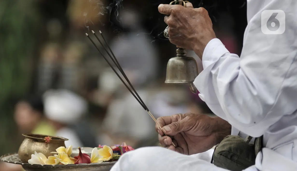 Pemuka agama menyembunyikan lonceng saat memimpin sembahyang Hari Raya Galungan di Pura Aditya Jaya, Rawamangun, Jakarta, Rabu (19/2/2020). Hari Raya Galungan yang merupakan hari kemenangan kebenaran (Dharma) atas kejahatan (Adharma) itu dirayakan setiap 210 hari sekali. (merdeka.com/Iqbal Nugroho)
