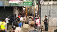 Petugas memblokade akses masuk ke gang-gang perumahan di kawasan Kampung Pulo. (Nafiysul Qodar/Liputan6.com)