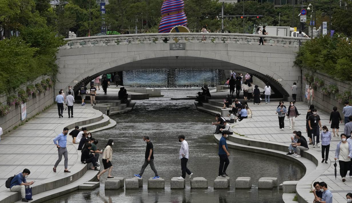 Orang-orang menyeberangi sungai Cheonggye di Seoul, Korea Selatan, Rabu (1/9/2021). Rekor harian kasus virus corona yang ditetapkan bulan lalu hanya sehari setelah para pejabat dengan hati-hati menyatakan harapan bahwa infeksi mungkin lambat. (AP Photo/Ahn Young-joon)