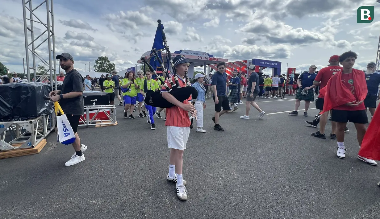 Suporter Skotlandia memainkan bagpipe saat berjalan di area fanzone Gillette Stadium, Foxborough, Amerika Serikat, Jumat (19/6/2026), menjelang laga melawan Maroko pada Piala Dunia 2026. Alunan musik tradisional tersebut menambah semarak suasana dan menjadi salah satu ciri khas dukungan Tartan Army kepada Timnas Skotlandia. (KLY Sports/Hery Kurniawan)