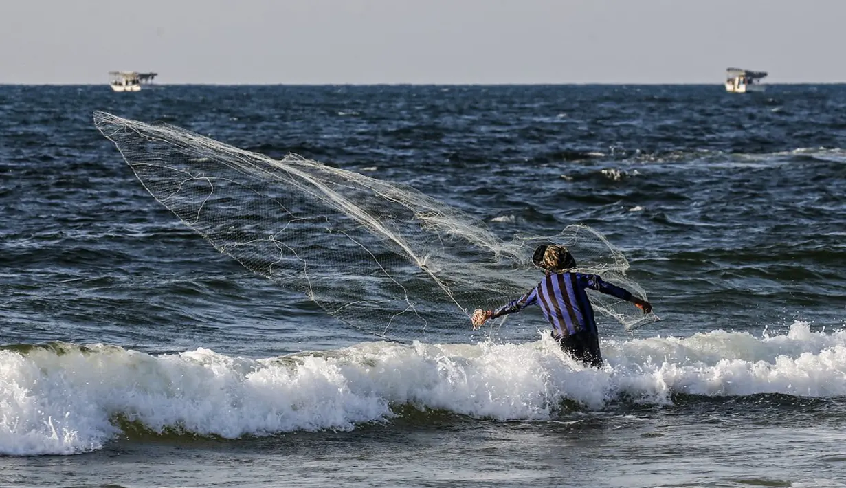 Seorang nelayan Palestina melemparkan jala ikan saat menangkap ikan di Laut Mediterania, Rafah, Jalur Gaza, Rabu (2/9/2020). (SAID KHATIB/AFP)
