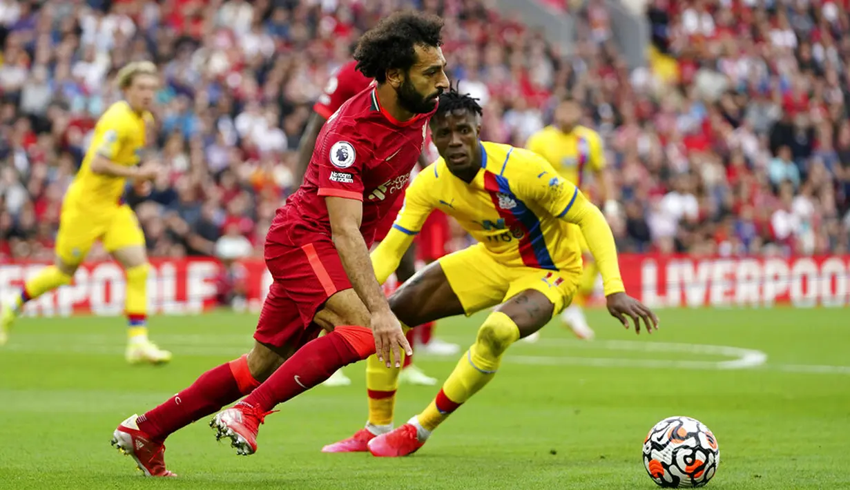 Pemain Liverpool Mohamed Salah berlari dengan bola yang disaksikan oleh pemain Crystal Palace Wilfried Zaha (kanan) pada pertandingan Liga Inggris di Stadion Anfield, Liverpool, Inggris, Sabtu (18/9/2021). Liverpool menang telak 3-0. (AP Photo/Jon Super)