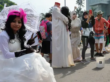 Seniman dengan kostum none Belanda berpose saat kegiatan Car Free Day di Bundaran HI di Jakarta, Minggu, (12/11). Mereka membuka kesempatan kepada warga yang ingin foto bersama. (Liputan6.com/Fery Pradolo)