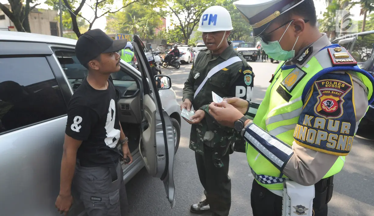 Petugas kepolisian memeriksa kelengkapan dokumen pengendara mobil saat melakukan razia gabungan di kawasan Naggewer,  Bogor, Selasa (18/9). Razia rutin itu melibatkan unsur Polri dengan Dispenda, POM TNI dan Dinas Perhubungan. (Merdeka.com/Arie Basuki)