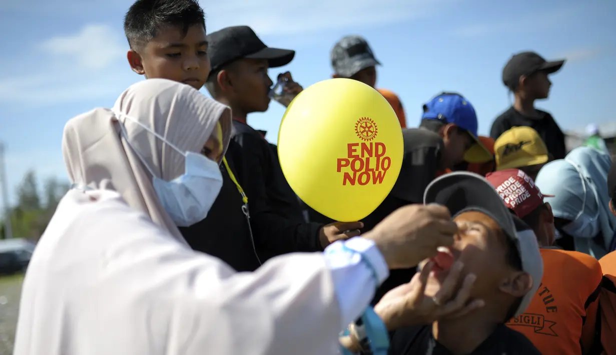 Pekerja medis memberikan vaksin kepada seorang anak laki-laki saat kampanye imunisasi polio di Sigli Town Square di Pidie, Aceh, Senin (28/11/2022). Kementerian Kesehatan melakukan vaksinasi massal guna mencegah meluas kasus polio di daerah itu sehubungan terjadinya penambahan kasus menjadi empat anak terinfeksi polio type 2 di provinsi Aceh. (AP Photo/Riska Munawarah)