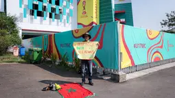Suporter Maroko, Mohammad Aziz Mrabat menunggu kedatangan bus Timnas Maroko U-17 sambil membentangkan poster bertuliskan "Maroko, menang atau kalah aku tetap mencintaimu" menjelang laga kedua Grup A Piala Dunia U-17 2023 antara Timnas Maroko U-17 melawan Timnas Ekuador U-17 di Stadion Gelora Bung Tomo (GBT), Surabaya, Senin (14/11/2023). (Bola.com/Bagaskara Lazuardi)