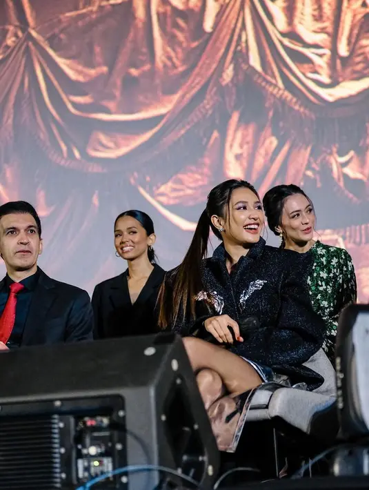 Sementara itu, untuk outfit press conference, ia memakai jaket hitam dengan detail sayap. Dan rok silver dengan siluet mullet. [Foto: @miktambayong]