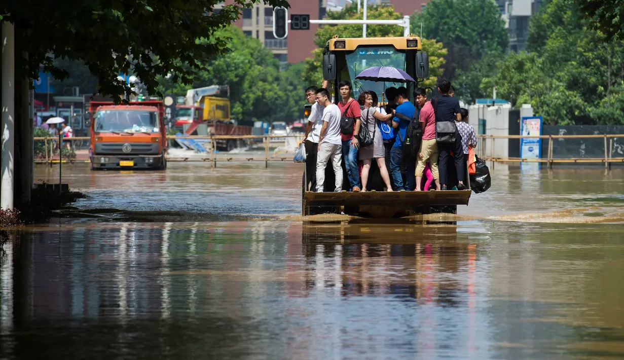 Sejumlah warga berada di ekskavator saat menuju kantor untuk bekerja di Wuhan, provinsi Hubei, (8/7). Curah hujan terberat yang mengguyur China selama beberapa hari terakhir telah mengakibatkan banjir merendam sejumlah daerah. (REUTERS/Stringer)