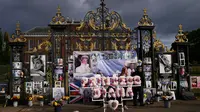 Seorang wanita berdiri di antara bunga dan pesan peringatan untuk Putri Diana yang dipajang di gerbang Istana Kensington, London, Rabu (31/8/2022). Hari ini menandai peringatan 25 tahun kematian Putri Diana dalam kecelakaan mobil di Paris. (AP Photo/Alastair Grant)