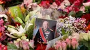 Sebuah foto kecil Raja Harald V dari Norwegia terlihat di antara bunga-bunga di lokasi penghormatan sementara di alun-alun Istana Kerajaan di Oslo, Norwegia, Jumat, 28 Agustus 2026. (AFP/ Odd Andersen)