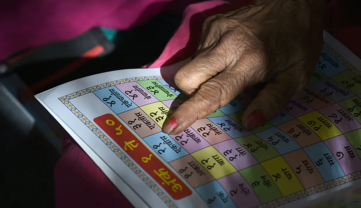 Nenek Ramabai Khandakre (69) membaca buku selama mengikuti kegiatan di Sekolah Aajibaichi Shaala, Desa Fangane, India, pada 1 Maret 2017. (AFP Photo / Indranil Mukherjee)