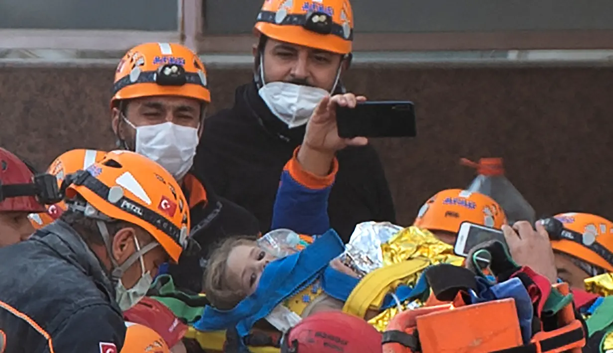Petugas penyelamat membawa Ayda Gezgin, 3, keluar dari reruntuhan gedung apartemen setelah gempa bumi dahsyat di kota Izmir, Turki, Selasa (3/11/2020). Ayda Gazgin berhasil diselamatkan dari bawah reruntuhan bangunan setelah terkubur selama 4 hari atau sekitar 91 jam. (Yasin AKGUL / AFP)