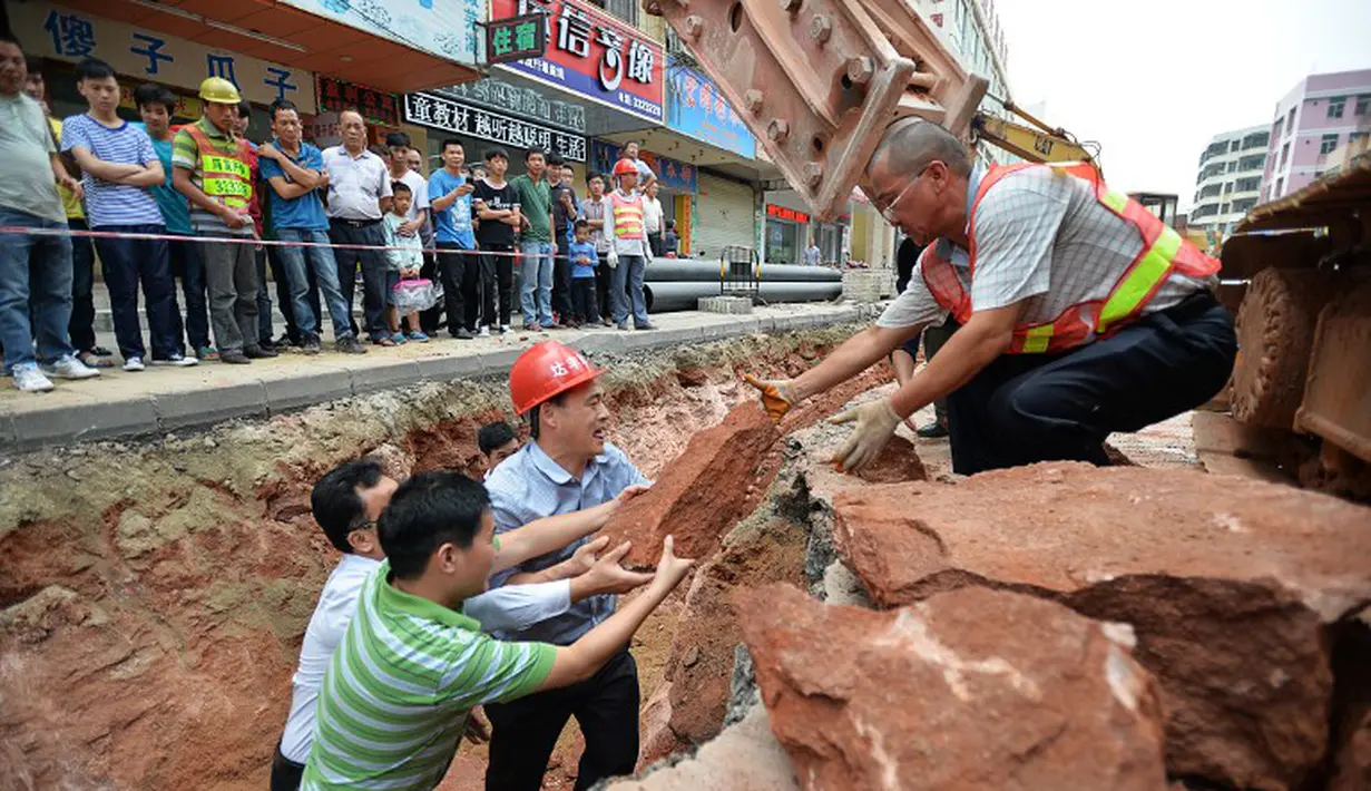 Sejumlah petugas berusaha mengangkat fosil telur Dinosaurus , Heyuan, Tiongkok, Kamis (23/4/2015). Fosil ditemukan secara tidak sengaja saat perbaikan jalan untuk pemasangan pipa(AFP Photo/China Out)