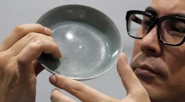 Staf Balai Lelang Sotheby menunjukkan mangkuk berusia 1.000 tahun dari Dinasti Song di Hong Kong, Selasa (3/10). Terjual sekitar Rp510,4 miliar, mangkuk berdiameter 13 cm itu memecahkan rekor lelang dunia untuk barang-barang keramik China. (AP/Kin Cheung)