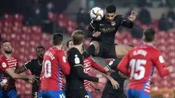 Bek Barcelona, Ronald Araujo (atas) menyundul bola dari ancaman pemain Granada dalam laga perempatfinal Copa del Rey 2020/21 di Nuevo Los Carmenes Stadium, Rabu (3/2/2021). Barcelona menang 5-3 (2-2) atas Granada melalui babak extra time. (AFP/Jorge Guerrero)