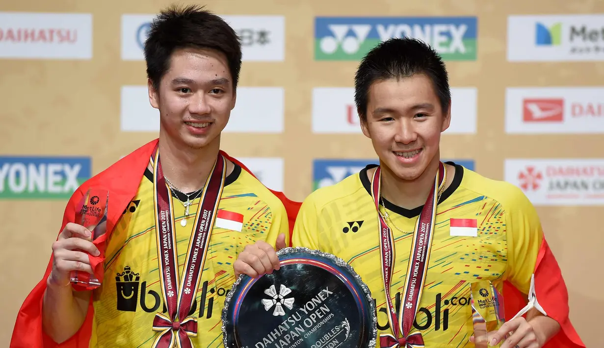 Pasangan ganda putra Indonesia, Kevin Sanjaja Sukamuljo (kiri) dan Marcus Feraidi Gideon berpose dengan trofi juara Japan Open 2017 di Tokyo, Jepang, (24/9). Kevin/Marcus  mengalahkan wakil tuan rumah, Takuto Inoue/Yuki Kaneko. (AFP Photo/Toru Yamanaka)