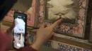 Seorang pengunjung memberi makan pasta malt ke kucing Persia sambil mengambil foto, di Museum Kucing Persia di Teheran, Iran, pada 5 Desember 2021. Didirikan di sebuah rumah tua pada tahun 2020, Museum Kucing Persia ini berawal dari kafe serba guna dan pameran kucing. (AP Photo/Vahid Salemi)