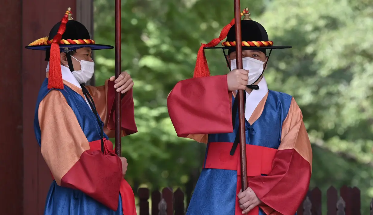 Anggota 'penjaga istana' yang mengenakan masker berdiri untuk turis di gerbang utama Istana Deoksugung di Seoul (4/9/2020). Korea Selatan melaporkan 198 kasus Covid-19 baru pada 4 September, hari ke-22 berturut-turut meningkat tiga digit. (AFP/Jung Yeon-je)