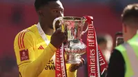 Kiper Manchester United, Andre Onana berpose dengan trofi Piala FA 2023/2024 usai menumbangkan Man City di final, Sabtu (25/5/2024). (AP Photo/Ian Walton)