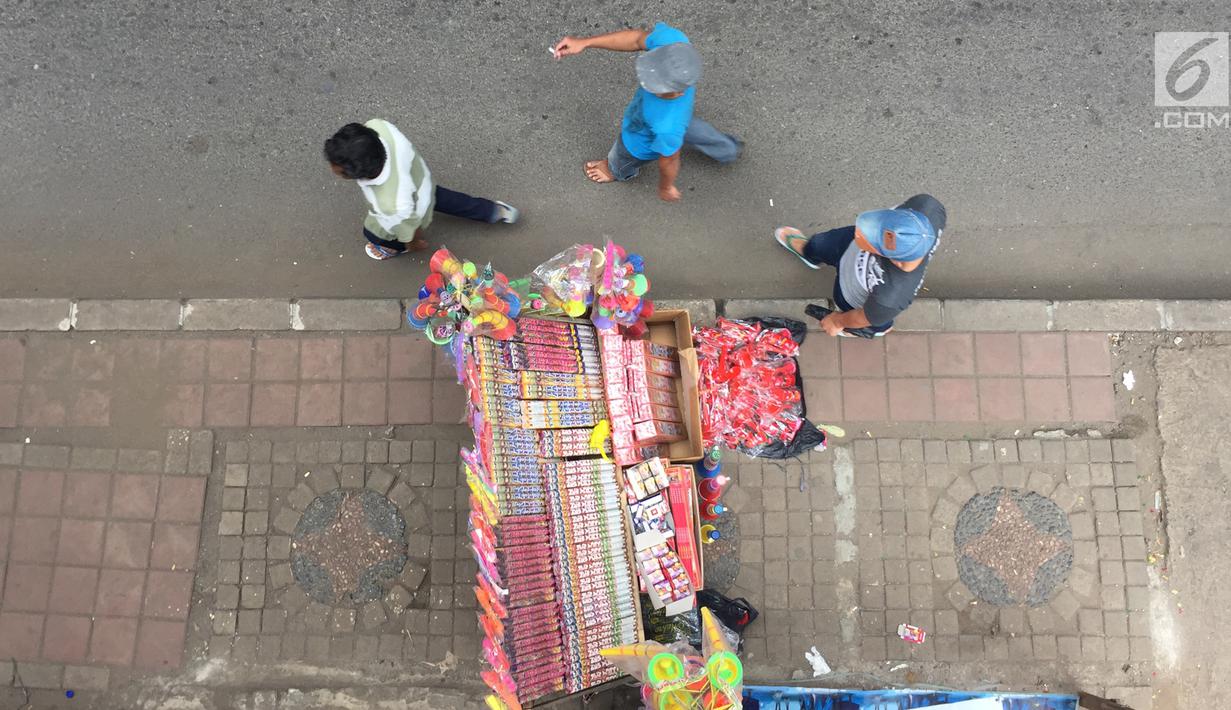 Pejalan kaki melintas di dekat lapak penjual kembang api di  kawasan Pasar Gembrong, Jakarta, Kamis (28/12). Menjelang perayaan malam pergantian tahun, penjual kembang api mulai meramaikan sejumlah sudut Ibukota. (Liputan6.com/Immanuel Antonius)