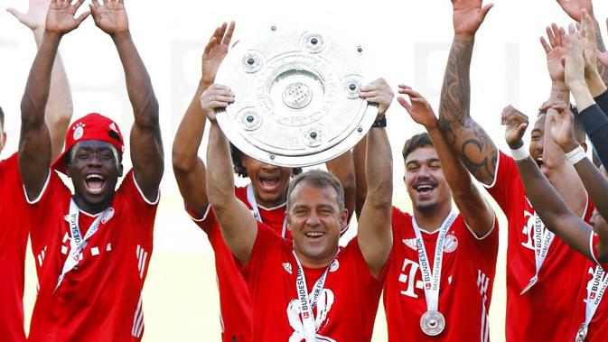 Pelatih Bayern Munchen, Hansi Flick, mengangkat trofi juara Bundesliga usai melawan Wolfsburg di Volkswagen Arena, Sabtu (27/6/2020). Kemenangan itu membuat Bayern kokoh di puncak klasemen sekaligus mengunci gelar juara Bundesliga. (AP/Kai Pfaffenbach)