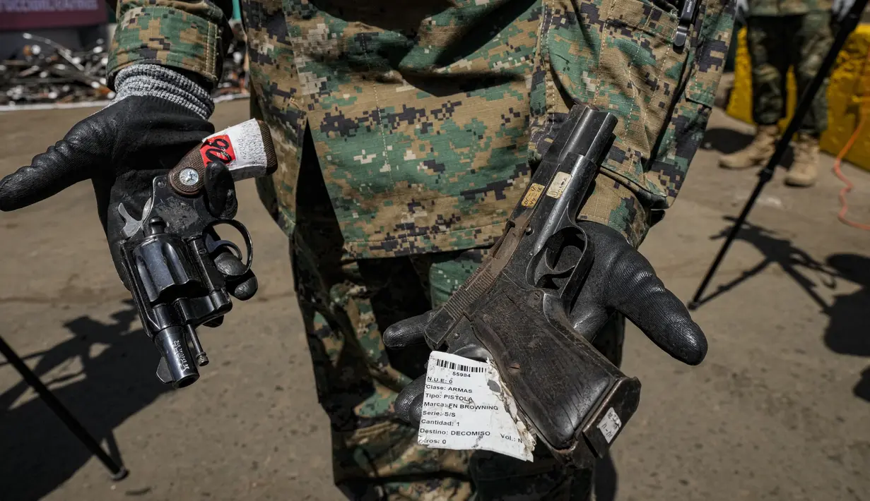 Seorang perwira Angkatan Darat Chile menunjukkan senjata yang secara sukarela diserahkan ke polisi atau disita, sebelum dilebur di Santiago, Chile, Kamis (11/11/2021). Lebih dari 13.600 senjata ilegal dihancurkan, menurut komisi nasional yang mengatur senjata. (AP Photo/Esteban Felix)