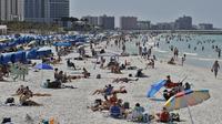Pengunjung menikmati Clearwater Beach di Florida, Amerika Serikat, Rabu (18/3/2020). Para pengunjung diminta menjaga jarak satu sama lain untuk mengurangi risiko penyebaran virus corona COVID-19. (AP Photo/Chris O'Meara)