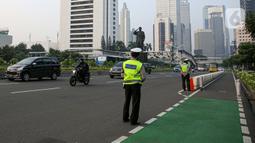 Polisi saat menertibkan pesepeda yang berada di luar jalur di kawasan Sudirman-Thamrin, Jakarta Pusat, Rabu (2/6/2021). Sepeda road bike diperbolehkan untuk melintas di Jalan Sudirman-Thamrin pada hari kerja Senin-Jumat, namun dibatasi dari pukul 05.00-06.30 WIB. (Liputan6.com/Faizal Fanani)