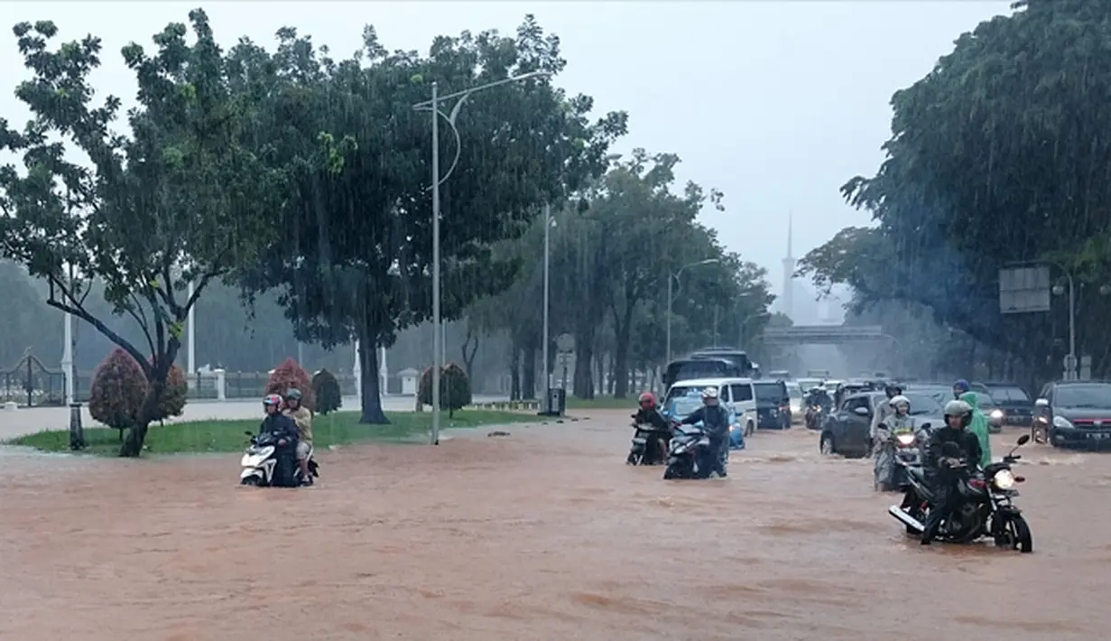 Pengguna jalan melintasi banjir yang merendam jalan di depan Istana Merdeka, Jakarta, Senin (9/2/2015).(Antara Foto/Fanny Octavianus)