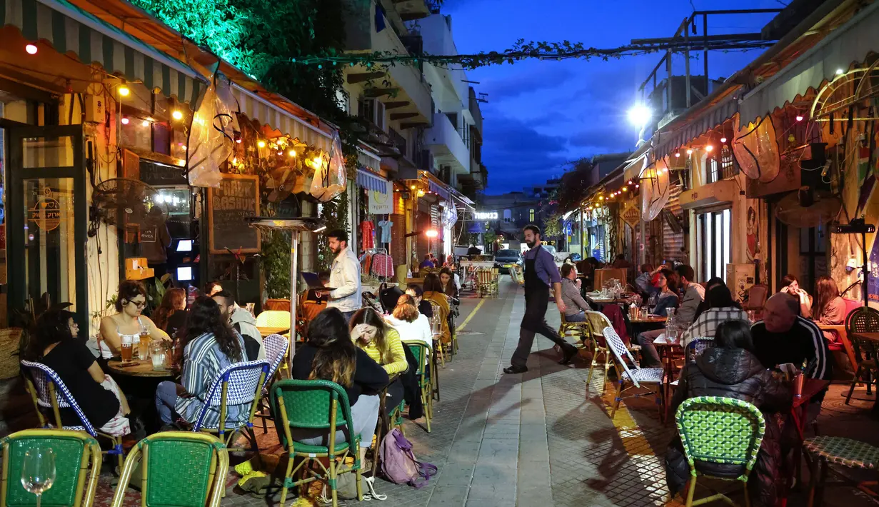 Orang-orang makan di sebuah restoran di kota pesisir Israel, Tel Aviv, Minggu (7/3/2021). Israel mengambil langkah lain menuju keadaan normal pasca-pandemi, dengan sekitar 40 persen populasi sepenuhnya telah diinokulasi untuk melawan virus corona COVID-19.  (Emmanuel DUNAND/AFP)