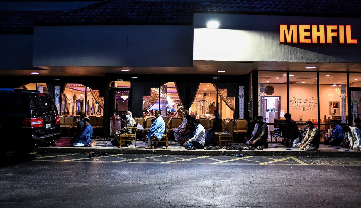 Pria Muslim melaksanakan salat di trotoar di luar restoran selama bulan suci Ramadhan di Lauderhill, Florida, Jumat (30/4/2021). Selama puasa Ramadhan, umat Islam tidak makan, minum, atau aktivitas seksual dari fajar hingga matahari terbenam. (CHANDAN KHANNA/AFP)
