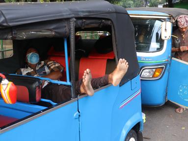 Pengemudi bajaj tengah beristirahat saat menunggu penumpang di kawasan Taman Puring , Jakarta, Minggu (11/7/2021). Dampak dari PPKM darurat membuat penghasilan para pengemudi bajaj menurun drastis hingga 70 pesen. (Liputan6.com/Angga Yuniar)