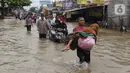 Seorang nenek digendong saat melintasi banjir yang menggenangi Jalan KH Hasyim Ashari, Tangerang, Banten, Kamis (2/1/2020). Banjir yang menggenangi jalan penghubung Jakarta- Tangerang tersebut mulai surut dan sudah bisa dilintasi pejalan kaki. (Liputan6.com/Angga Yuniar)