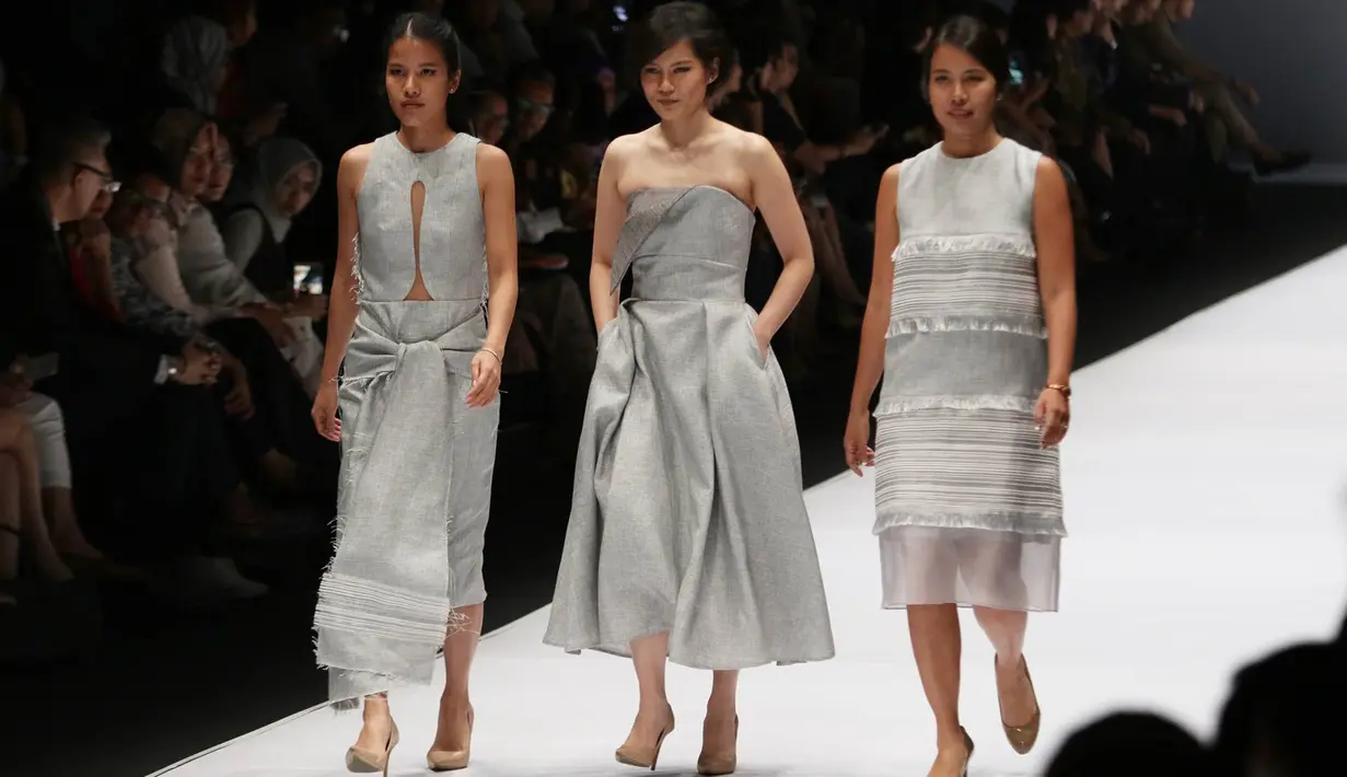 Desainer bersama dua modelnya mengenakan gaun berwarna perak saat parade desainer dalam acara pembukaan Jakarta Fashion Week 2017 di Senayan City, Jakarta, Sabtu (22/10). (Liputan6.com/Immanuel Antonius)