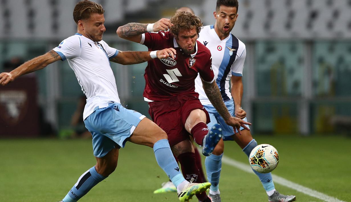 Penyerang Lazio, Ciro Immobile, berebut bola dengan pemain Torino pada laga lanjutan Serie A pekan ke-29 di Stadion Olimpico Grande Torino, Rabu (1/7/2020) dini hari WIB. Lazio menang 2-1 atas Torino. (AFP/Isabella Bonotto)
