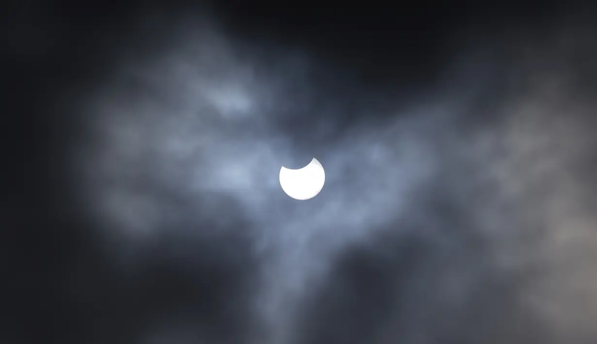 Gerhana matahari sebagian terlihat melalui tutupan awan dari Primrose Hill di pusat kota London, Kamis (10/6/2021).  (AFP/ Niklas Halle’n)
