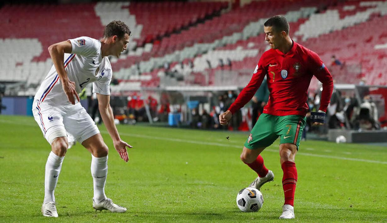 Striker Portugal, Cristiano Ronaldo, berusaha melewati bek Prancis, Benjamin Pavard, pada laga UEFA Nations League di Stadion Da Luz, Minggu (15/11/2020). Prancis menang dengan skor 1-0. (AP/Armando Franca)