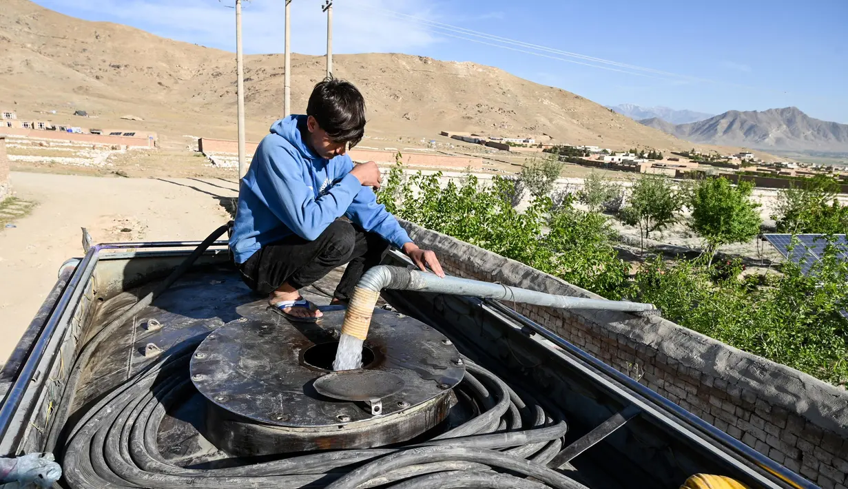 Dalam foto yang diambil pada 27 April 2025 ini, seorang anak laki-laki mengisi tangki air minumnya dari sebuah pompa di pinggiran kota Kabul, Afghanistan. (Wakil KOHSAR/AFP)