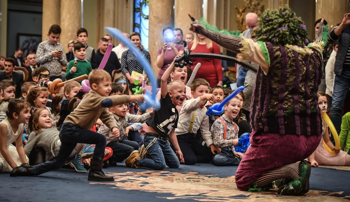 Anak-anak melihat aksi badut selama acara Natal di Istana Militer Nasional di Bucharest, Rumania, (21/12). Kemenhan Rumania mengadakan pertunjukan Natal untuk puluhan anak-anak Rumania yang ayahnya terbunuh dalam bertugas. (AFP Photo/Daniel Mihailescu)