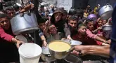 Para pengungsi Palestina berkumpul untuk mengambil makanan yang sudah dimasak dalam sebuah pembagian makanan di Jabalia, Jalur Gaza utara, pada 19 Mei 2025. (Bashar TALEB/AFP)