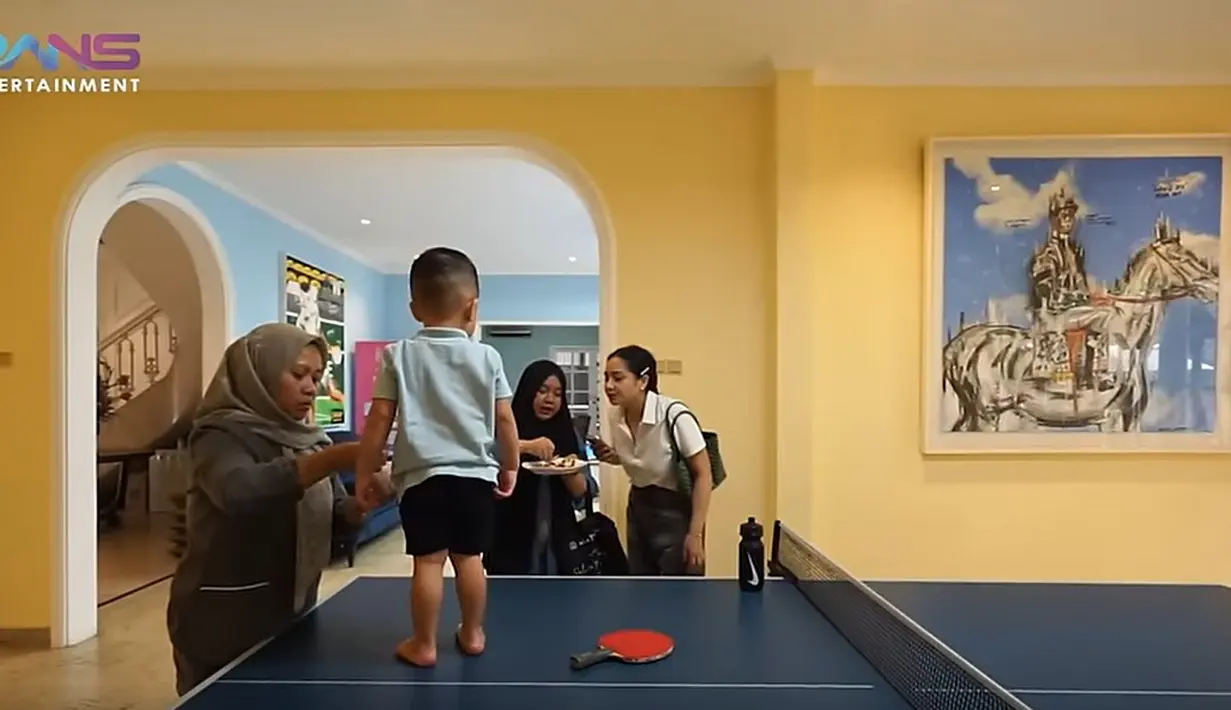 "Ja (Rayyanza), lihat mama disuapin Mbak Lala. Lihat Ja," kata Nagita kepada anak bungsunya yang asyik bermain tenis meja. Momen tersebut ada dalam video di saluran YouTube Rans Entertainment. 
 [Youtube/Rans Entertainment]