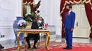 Presiden Indonesia Joko Widodo (kanan) menyaksikan Perdana Menteri Malaysia Muhyiddin Yassin menandatangani buku tamu di Istana Merdeka, Jakarta, Jumat (5/2/2021). Pertemuan di antaranya membahas isu perlindungan WNI, isu kawasan, dan isu global. (HANDOUT/INDONESIAN PRESIDENTIAL PALACE/AFP)