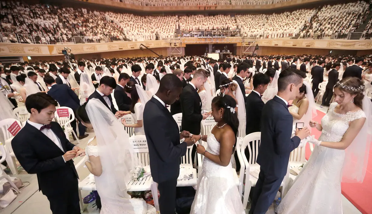 Pasangan pengantin bertukar cincin dalam pernikahan massal di Cheong Shim Peace World Center, Gapyeong, Korea Selatan, Senin (27/8). Acara ini diikuti sekitar 3.800 pasangan pengantin. (AP Photo/Ahn Young-joon)