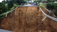 Orang-orang yang terlantar berdiri dekat jembatan yang hanyut di Ntuzuma, luar Durban, Afrika Selatan, 12 April 2022. Hujan berkepanjangan dan banjir di Provinsi KwaZulu-Natal Afrika Selatan telah merenggut puluhan nyawa, menurut pejabat setempat. (AP Photo)