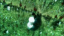Seorang pengunjung memegang lampu saat berpose di instalasi ilusi optik dalam pameran Imagine Your Museum of Art di Beijing, Tiongkok, Jumat (2/10/2015). (REUTERS/Jason Lee)