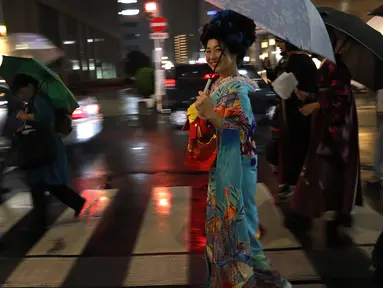 Seorang wanita Jepang tersenyum mengenakan pakaian tradisional saat berjalan di jalan setelah menghadiri peragaan busana kimono di Oita (18/10/2019). Pada zaman sekarang, kimono berbentuk seperti huruf "T", mirip mantel berlengan panjang dan berkerah. (AP Photo/Christophe Ena)