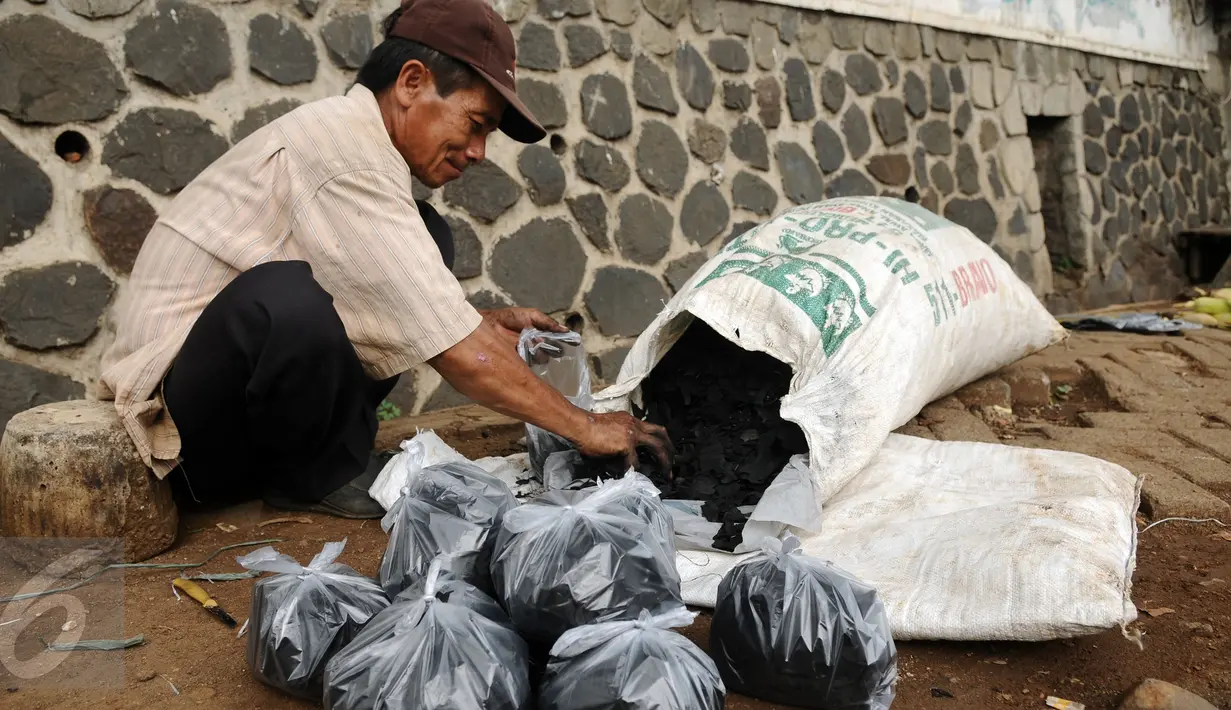 Seorang pedagang arang mengemas dagangannya di Jalan Lapangan Tembak Pasar Rebo, Jakarta, Kamis (31/12/2015). Ia mengaku menjual arang seharga Rp 5.000,- per bungkus. (Liputan6.com/Helmi Fithriansyah)