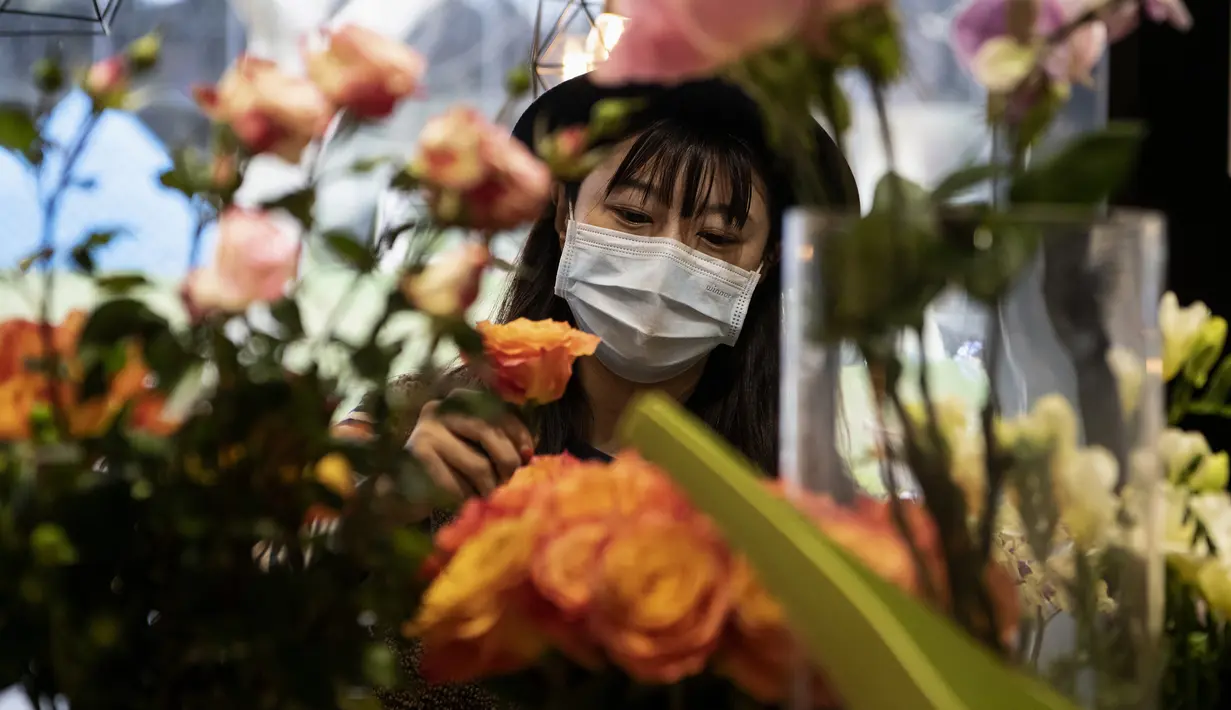 Penjual bunga Zhao Yuanyuan mengenakan masker mengatur bunga menjelang Hari Valentine di tokonya di Shanghai (12/2/2020). Wabah virus corona COVID-19 masih membayangi perayaan Hari Valentine di negara China. (AFP Photo/Noel Celis)