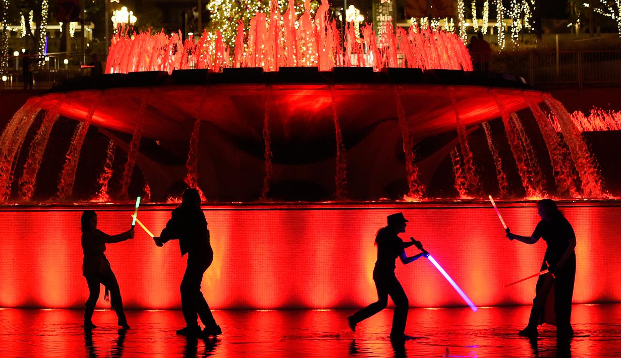 Sejumlah orang penggemar film Star Wars beradu pedang saat mengikuti Glow Battle Tour di Grand Park, Los Angeles (15/12). Mereka melakukan perang pedang bak di film Star Wars. (Photo by Chris Pizzello/Invision/AP)